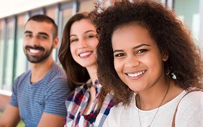 Three diverse students sitting in a row smiling